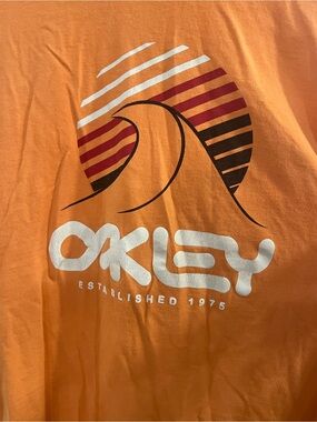 Oakley Orange Tee with White Logo and Sunset Wave Graphic